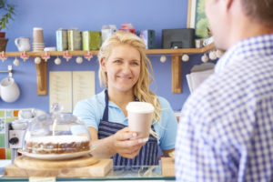 Waitress In Cafe Serving Customer With Coffee