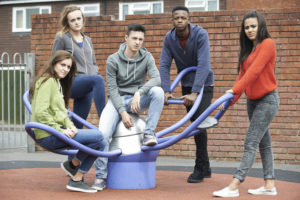 Gang Of Teenagers Hanging Out In Children's Playground