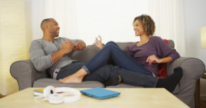 Black couple using electronic devices on couch