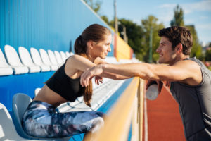 Young beautiful couple standing and talking on athletics track field